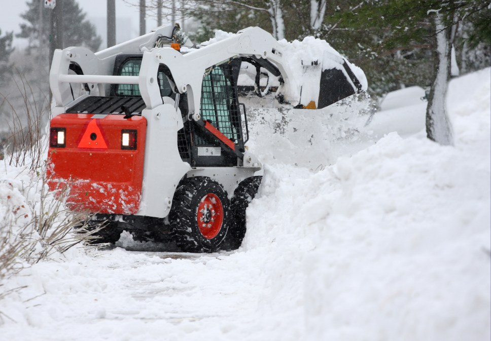 Skid steer clearing deep snow during a winter storm